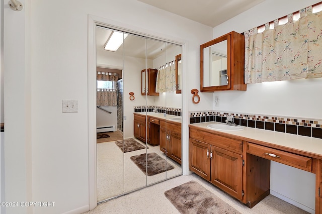 bathroom featuring baseboard heating, tasteful backsplash, and vanity