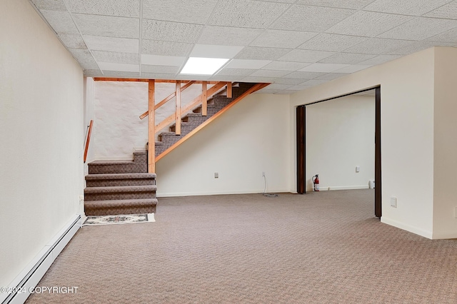 basement featuring a paneled ceiling, carpet floors, and a baseboard heating unit