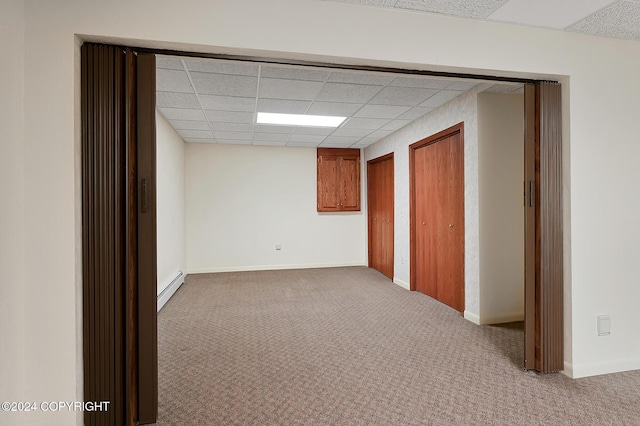 carpeted spare room featuring a paneled ceiling and a baseboard radiator