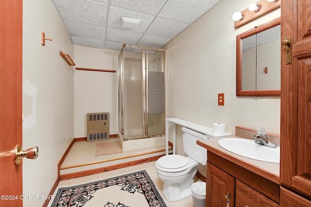 full bathroom featuring a drop ceiling, vanity, toilet, enclosed tub / shower combo, and heating unit