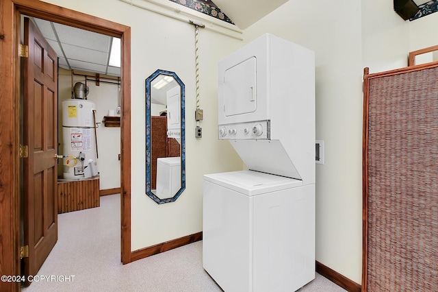 washroom with strapped water heater and stacked washer and clothes dryer