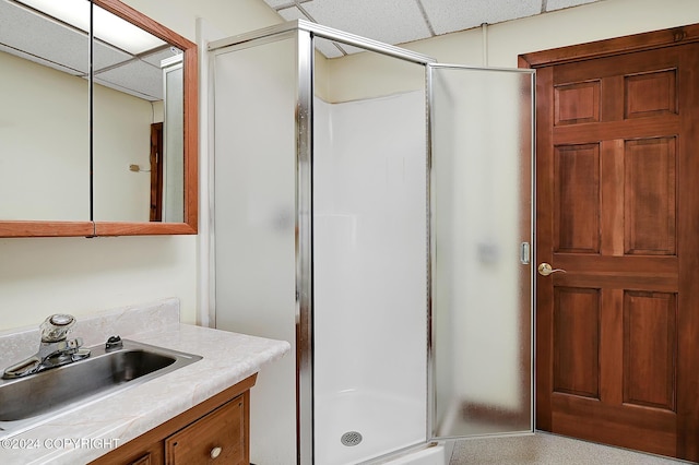 bathroom featuring a paneled ceiling, vanity, and walk in shower