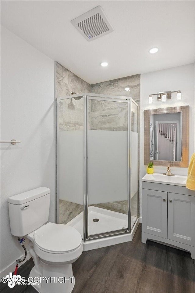 bathroom featuring hardwood / wood-style floors, vanity, a shower with shower door, and toilet