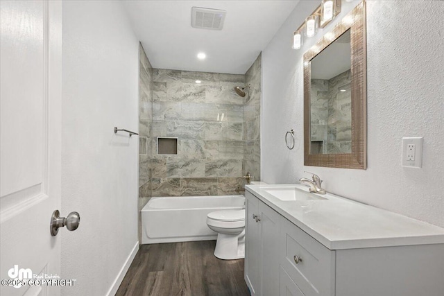 full bathroom featuring vanity, wood-type flooring, tiled shower / bath combo, and toilet