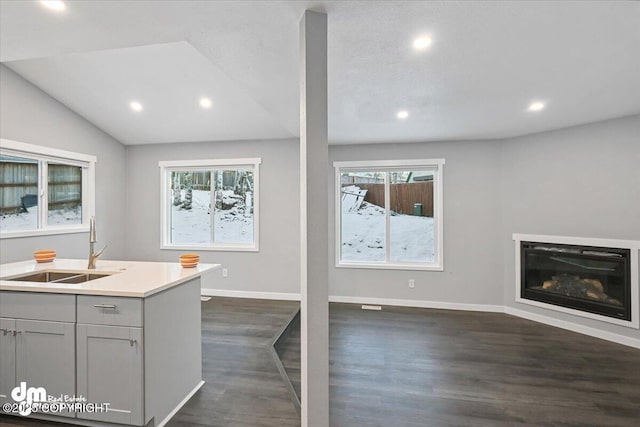 kitchen with gray cabinetry, sink, a center island with sink, dark hardwood / wood-style floors, and lofted ceiling