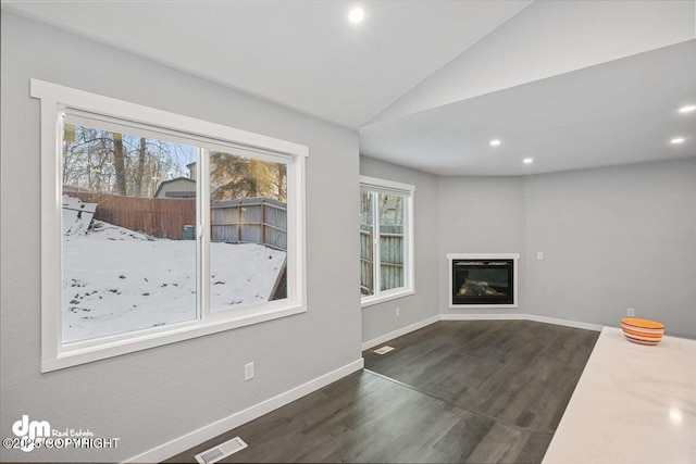 unfurnished living room featuring dark hardwood / wood-style flooring, a healthy amount of sunlight, and lofted ceiling