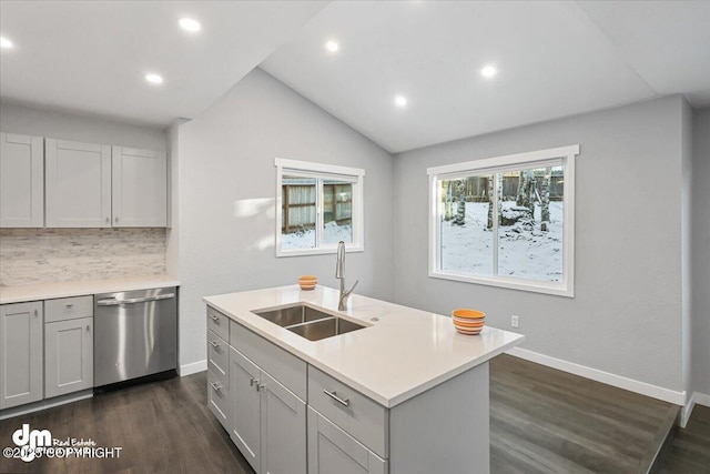 kitchen with lofted ceiling, backsplash, a center island with sink, sink, and stainless steel dishwasher