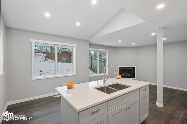 kitchen with a center island with sink, vaulted ceiling, dark hardwood / wood-style floors, and sink