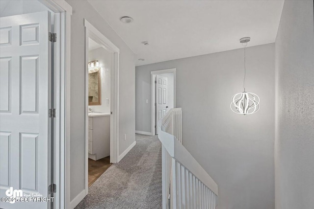 hall with carpet flooring and an inviting chandelier