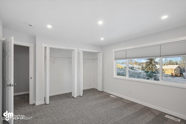 unfurnished bedroom featuring carpet and multiple closets