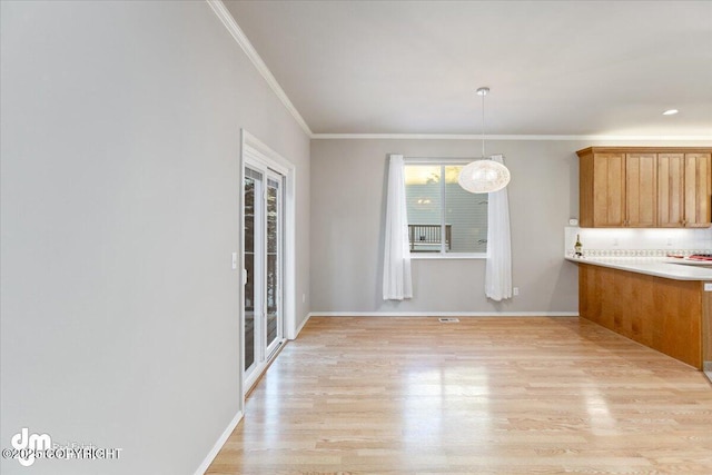 kitchen with light wood-type flooring, decorative light fixtures, and ornamental molding