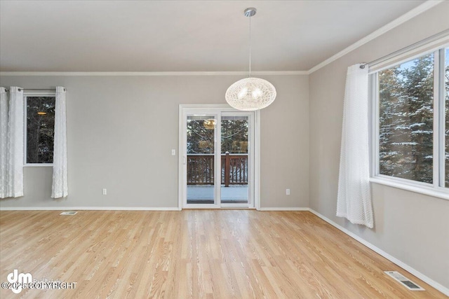 unfurnished room featuring a notable chandelier, light wood-type flooring, and crown molding