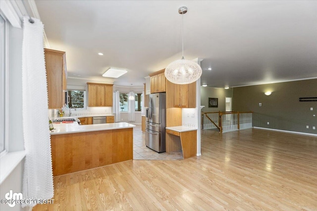 kitchen with hanging light fixtures, light hardwood / wood-style flooring, tasteful backsplash, kitchen peninsula, and stainless steel appliances