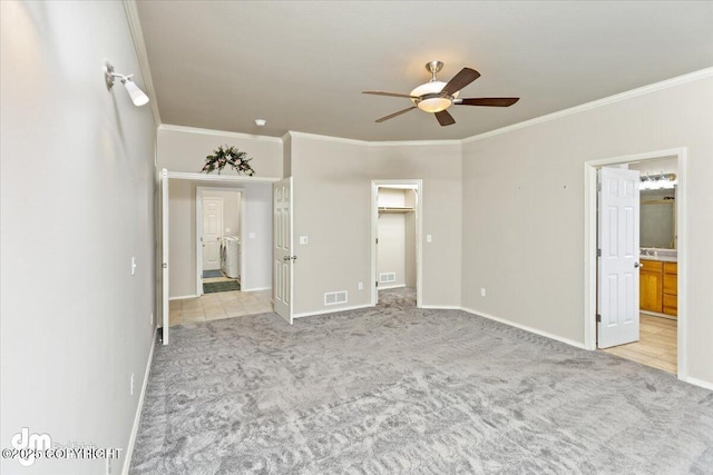 unfurnished bedroom featuring light carpet, ensuite bath, ceiling fan, crown molding, and a spacious closet