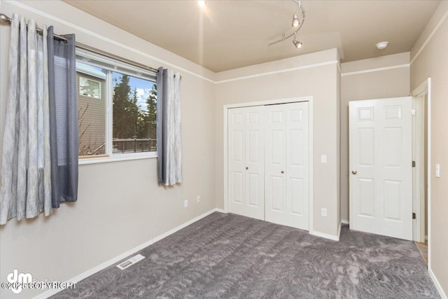 unfurnished bedroom with a closet and dark colored carpet