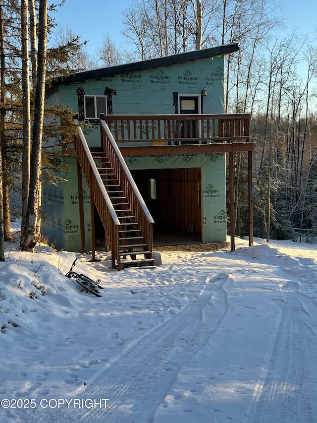 snow covered rear of property with a deck