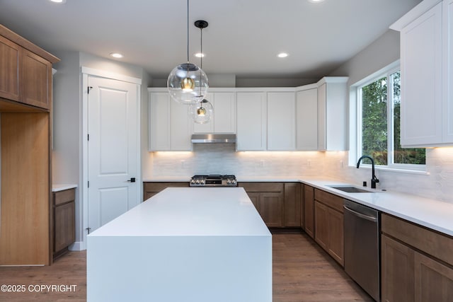 kitchen featuring light wood-type flooring, stainless steel dishwasher, a kitchen island, and sink