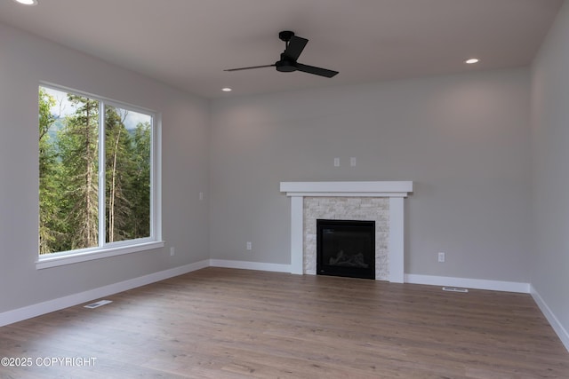 unfurnished living room with ceiling fan, wood-type flooring, and a fireplace