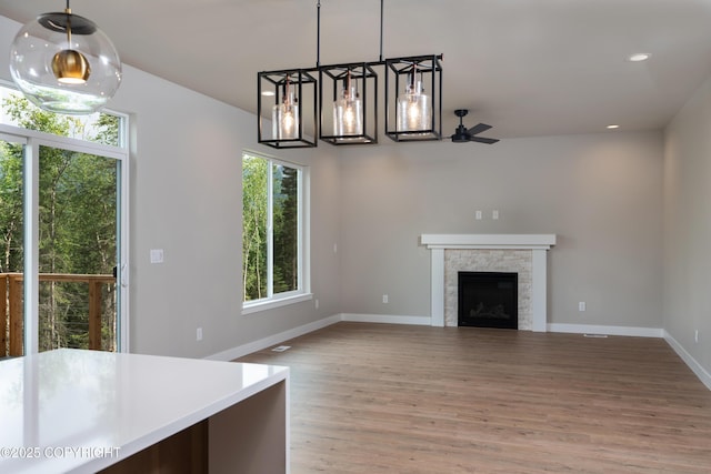 unfurnished living room with ceiling fan, a fireplace, and wood-type flooring