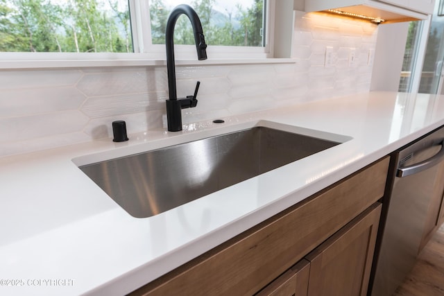 interior details featuring decorative backsplash, dishwasher, and sink