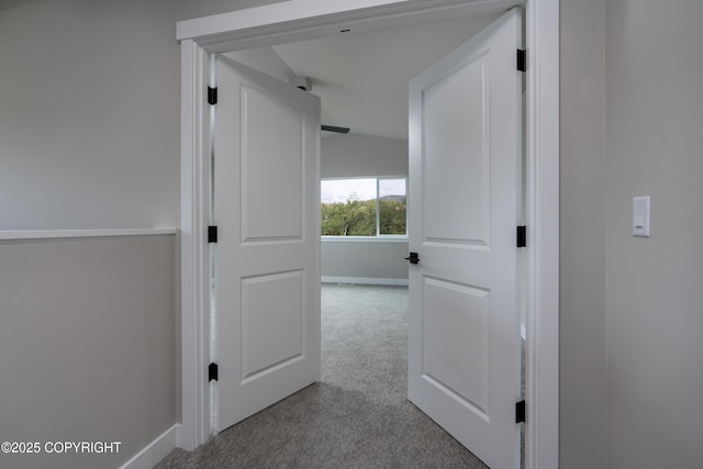 hallway featuring light carpet and vaulted ceiling