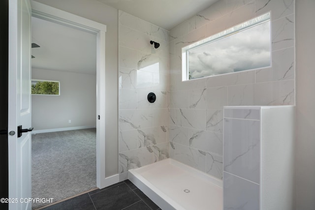 bathroom with a tile shower and tile patterned flooring