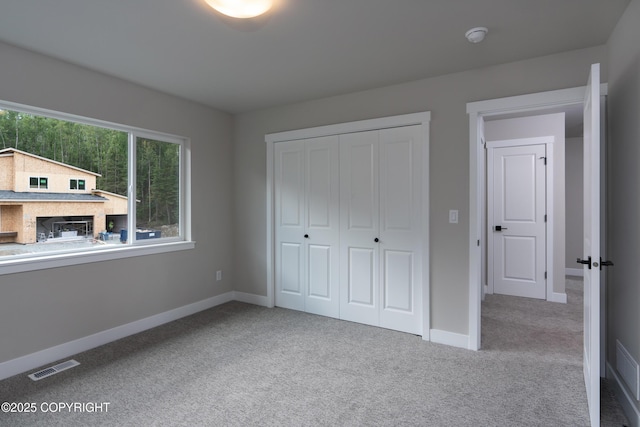 unfurnished bedroom featuring light carpet and a closet