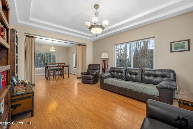 living room with a tray ceiling, a chandelier, and hardwood / wood-style floors