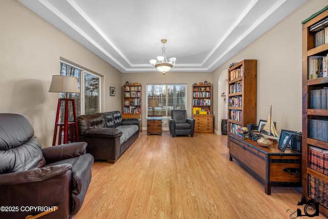 living area featuring light hardwood / wood-style floors, a raised ceiling, and a notable chandelier