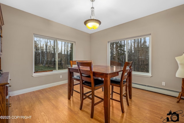 dining area with light hardwood / wood-style floors and a baseboard heating unit