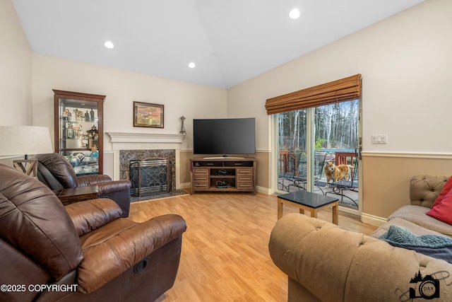 living room featuring wood-type flooring, vaulted ceiling, and a fireplace