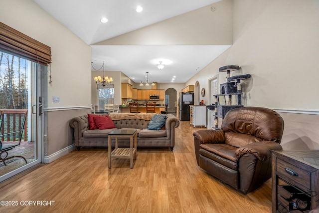 living room with vaulted ceiling, a notable chandelier, and light hardwood / wood-style flooring