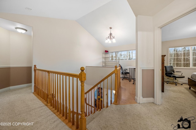 hall with lofted ceiling, light colored carpet, and a chandelier