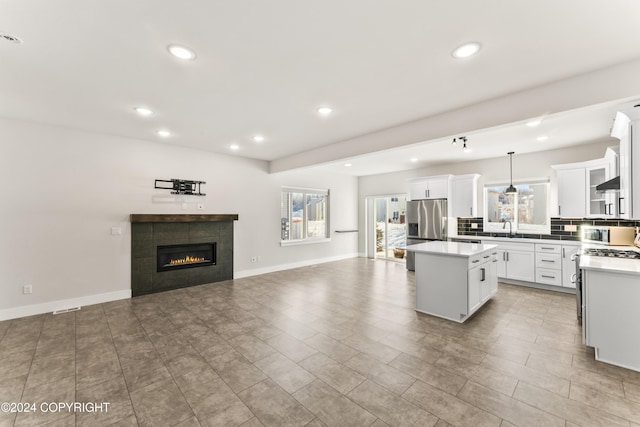 kitchen with white cabinets, decorative light fixtures, a kitchen island, stainless steel fridge with ice dispenser, and a tiled fireplace