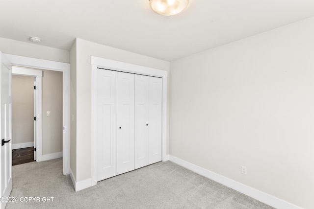 unfurnished bedroom with light carpet and a closet