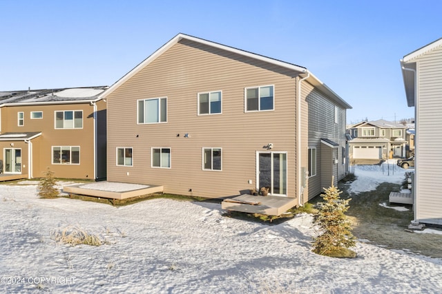 snow covered rear of property with a deck