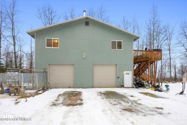 snow covered house featuring a garage and a deck