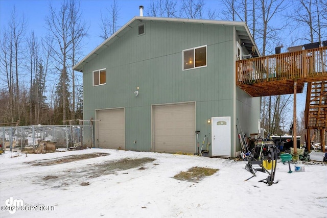 snow covered house with a deck and a garage