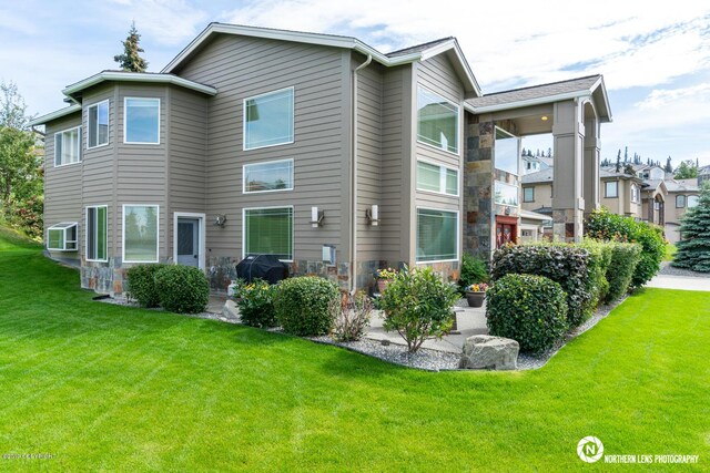 16643 Woods Pointe Cir, Anchorage, AK 99516 - rear view of house with a lawn and stone siding