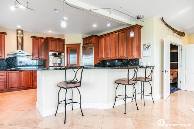 16643 Woods Pointe Cir, Anchorage, AK 99516 - kitchen with wall chimney exhaust hood, appliances with stainless steel finishes, decorative backsplash, a breakfast bar, and recessed lighting