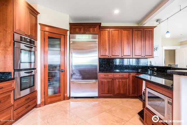 16643 Woods Pointe Cir, Anchorage, AK 99516 - kitchen with appliances with stainless steel finishes, tasteful backsplash, dark stone counters, brown cabinetry, and pendant lighting