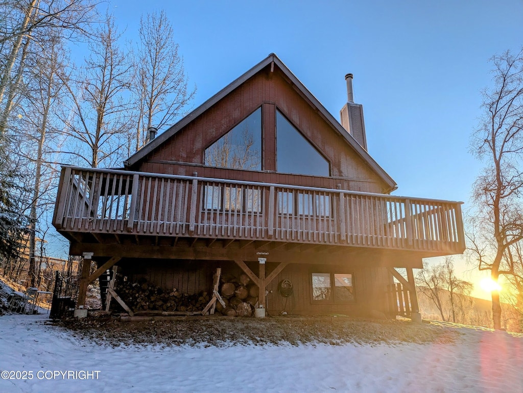 snow covered rear of property with a wooden deck