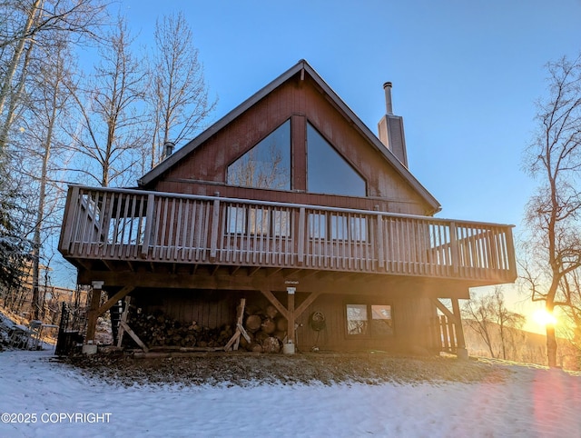 snow covered rear of property with a wooden deck