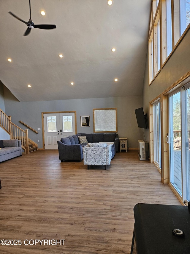 living room with ceiling fan, high vaulted ceiling, french doors, and light hardwood / wood-style floors