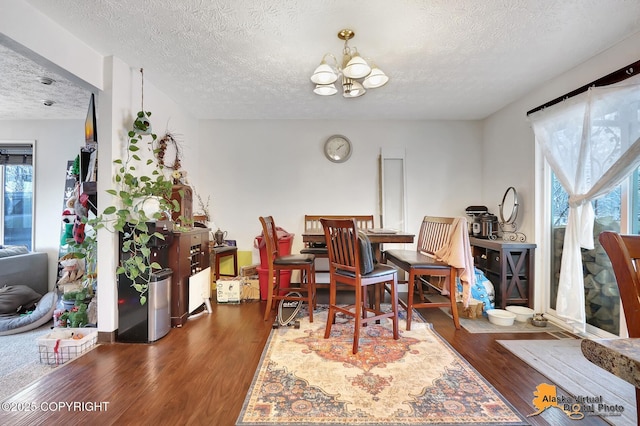 dining room with dark hardwood / wood-style floors, a healthy amount of sunlight, a textured ceiling, and a chandelier