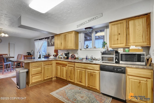 kitchen featuring kitchen peninsula, a textured ceiling, stainless steel appliances, sink, and light hardwood / wood-style flooring