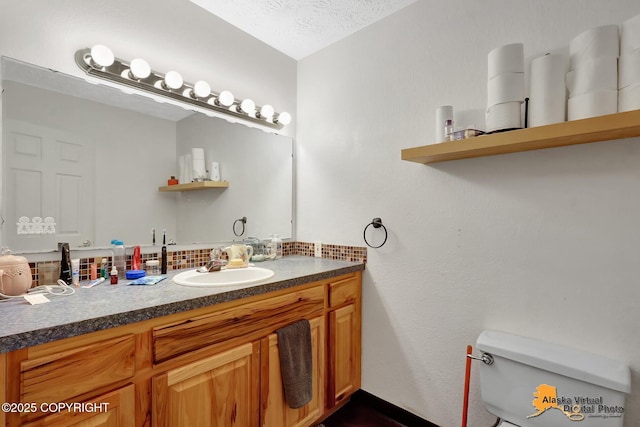 bathroom with vanity, toilet, and a textured ceiling