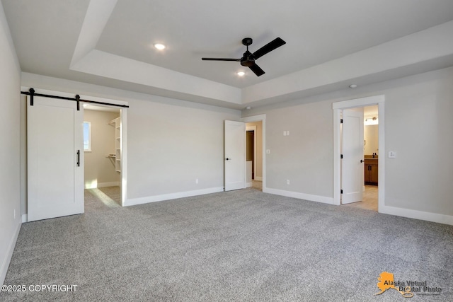 8803 Chalk Hill Loop, Anchorage, AK 99502 - unfurnished bedroom with a barn door, a raised ceiling, light colored carpet, connected bathroom, and recessed lighting