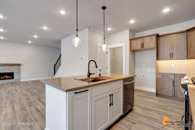 8803 Chalk Hill Loop, Anchorage, AK 99502 - kitchen with stainless steel appliances, light wood-type flooring, decorative backsplash, decorative light fixtures, and a kitchen island with sink