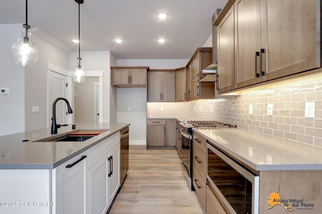 8803 Chalk Hill Loop, Anchorage, AK 99502 - kitchen featuring stainless steel appliances, light wood finished floors, tasteful backsplash, decorative light fixtures, and an island with sink